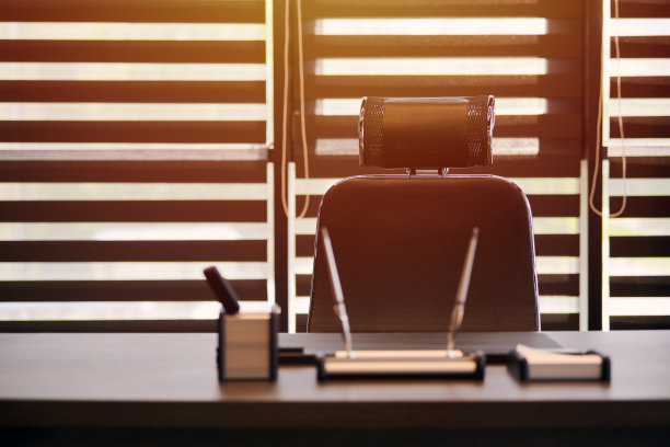 商业办公场所。阳光在工作场所为首席，老板或其他员工。桌子和舒适的椅子。光线透过半开的百叶窗图片下载