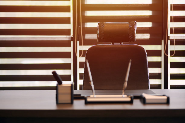 商业办公场所。阳光在工作场所为首席，老板或其他员工。桌子和舒适的椅子。光线透过半开的百叶窗图片下载