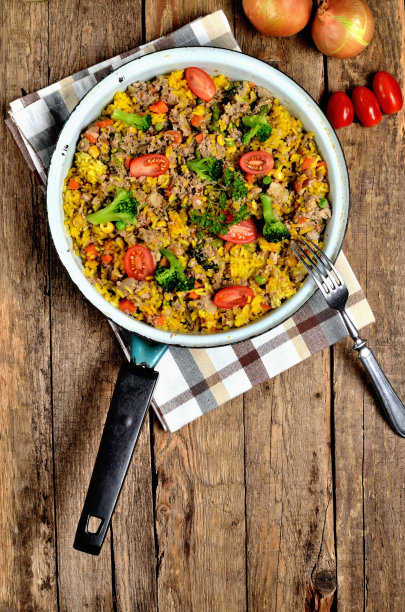 从上面看，金枪鱼烩饭与蔬菜，西红柿，花椰菜和欧芹在旧锅，洋葱，罐头和油在背景-垂直照片图片下载