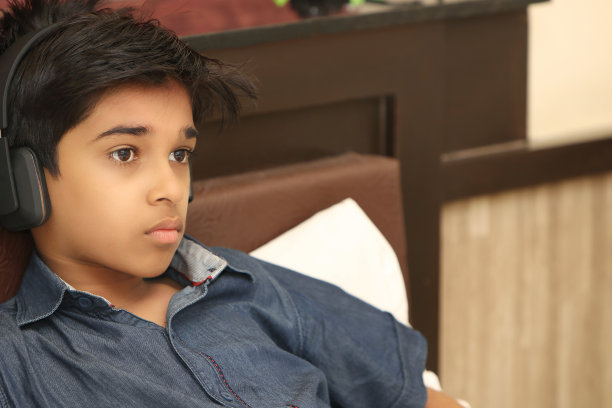 印度小男孩用耳机听音乐图片下载