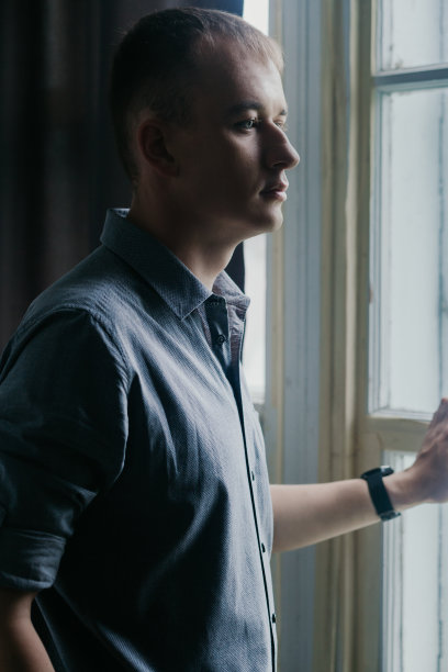 一个穿着灰色衬衫的帅哥站在窗边的时尚肖像图片下载