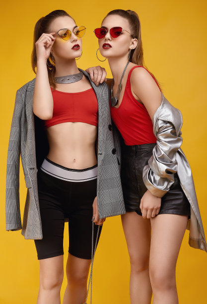 两个优雅迷人的时尚双胞胎女孩穿着时尚的红色上衣，黑色短裤图片下载