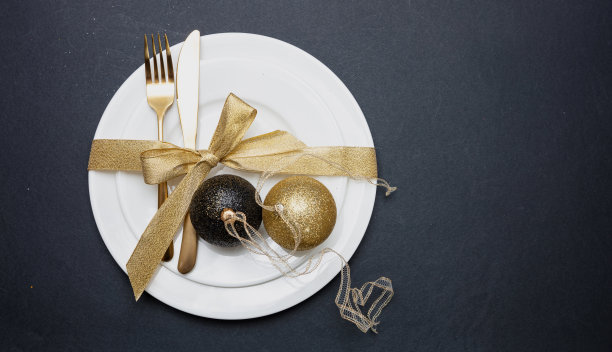 餐桌摆设，圣诞，新年。白色餐具上的金色餐具，黑色背景图片下载