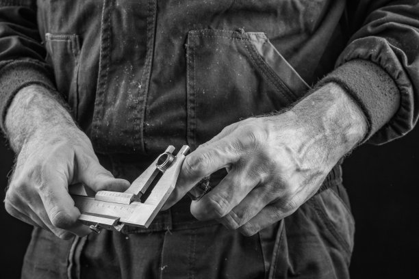 员工穿着带有卡钳的安全防护服。员工职业安全卫生用品和测量工具。黑暗的背景。图片下载