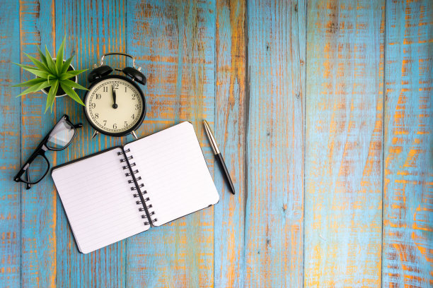 平铺构成的书，钢笔，植物，古董钟和眼镜在木制桌子上顶视图图片下载