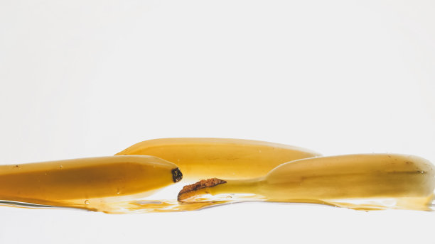 新鲜成熟的水果落在水里的特写照片。黄色的甜巴巴拉在白色的背景下溅水和流动图片下载