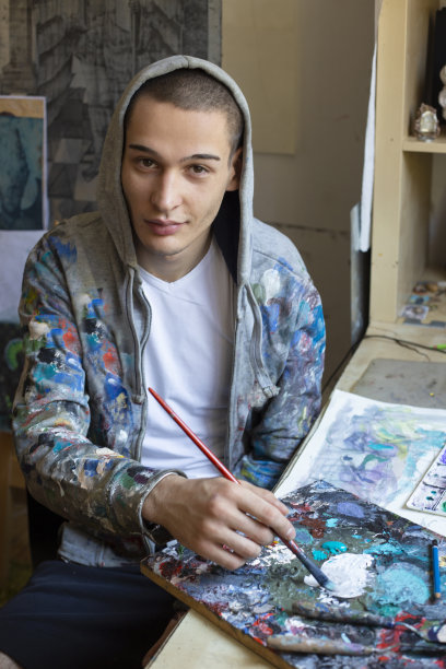 一个年轻人在他的画室里画画图片下载