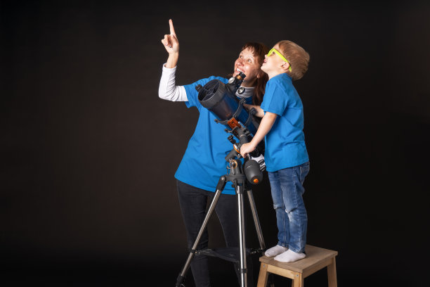 妈妈和儿子研究一个巨大的耐火望远镜并观察天空。图片下载