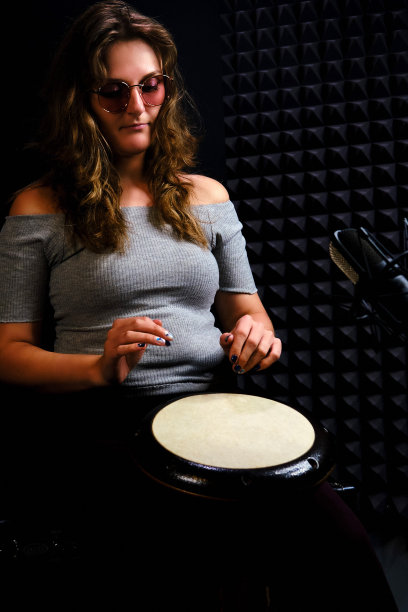 用非洲民族打击乐器演奏(水平图片)。一个年轻女子坐在录音室的地板上打鼓。图片下载