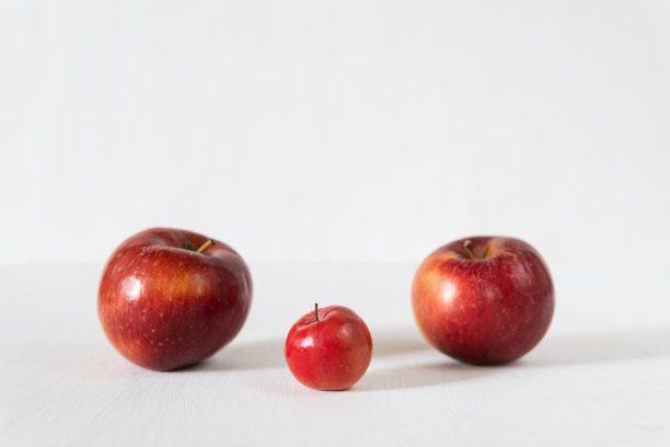 两只母苹果和一个小苹果在红色的背景图片下载