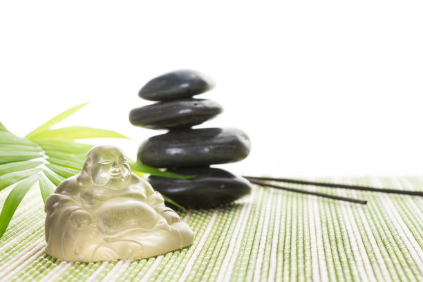 玻璃微笑佛与石头和叶子在竹席上，孤立在白色的背景。图片下载