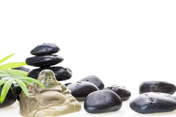 玻璃佛像微缩，黑色湿玄武岩石和绿叶，白色背景。图片下载