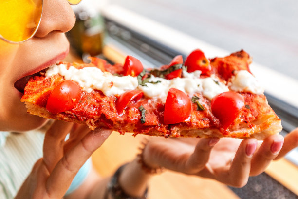 有趣的亚洲女孩戴着帽子吃佛卡夏披萨图片下载