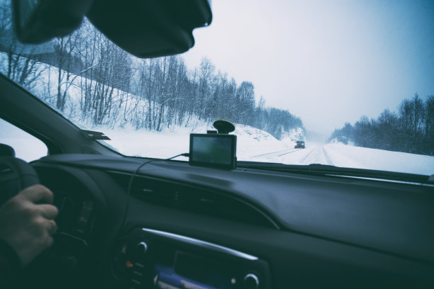 公路旅行-男人的手在方向盘上和在一个冬天的雪地上图片下载