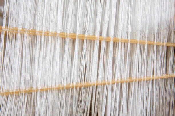 在手动织布机上近距离织造棉花。棉线在织布机上的选择性焦点。泰国棉手工制作的。朴素的织物的过程。用老式织布机织造织物的过程。图片下载