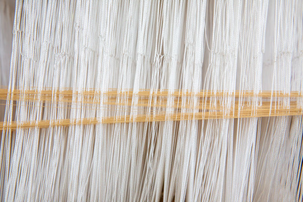 在手动织布机上近距离织造棉花。棉线在织布机上的选择性焦点。泰国棉手工制作的。朴素的织物的过程。用老式织布机织造织物的过程。图片下载