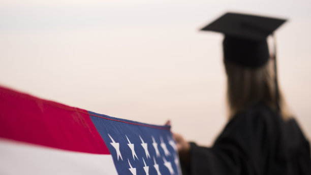 身着毕业服装的女子举着美国国旗图片下载