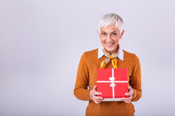 肖像成熟可爱漂亮甜美迷人的女士，穿着棕色上衣，拿着礼盒，想要惊喜。孤立在明亮的灰色背景图片下载