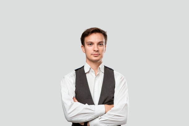 年轻的商人身穿白衬衫和灰色背心，双手交叉，自信满满。图片下载
