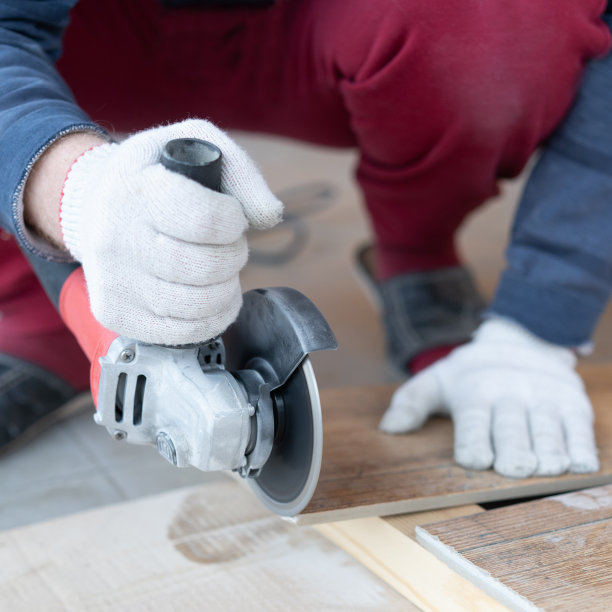 维修和装饰。一个男人用研磨机切割瓷砖。图片下载