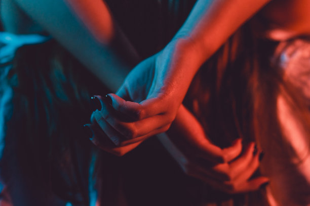 靠近女性年轻女子的女孩美丽的手女人躺在床上与黑色指甲油在黑暗的房间交叉手指在床单温柔的激情爱诱惑情感概念图片下载