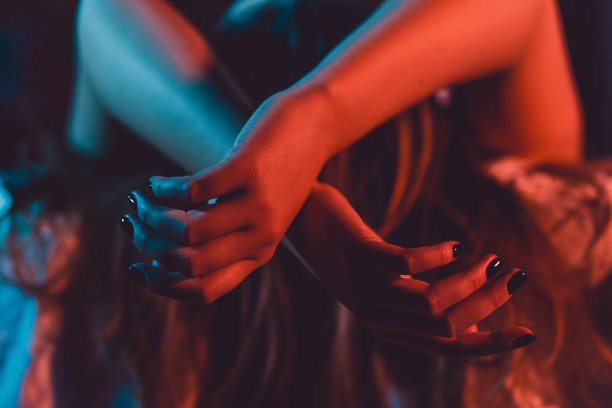 靠近女性年轻女子的女孩美丽的手女人躺在床上与黑色指甲油在黑暗的房间交叉手指在床单温柔的激情爱诱惑情感概念图片下载