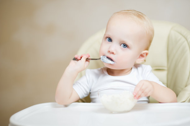 小孩坐在厨房的座位上吃粥图片下载