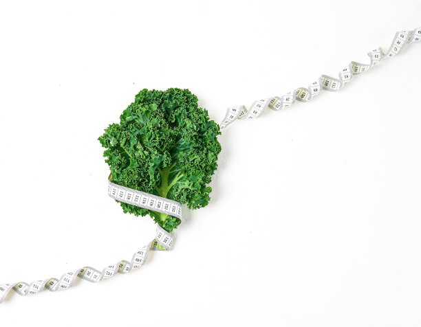 楼梯瘦身、减肥、健康生活的理念。羽衣甘蓝沙拉的创意图案和测量卷尺在白色的背景。图片下载