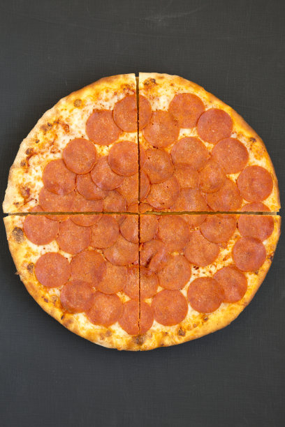 美味的意大利辣香肠披萨在黑色背景，俯视图。头顶上，从上面看，是平躺着的。特写镜头。图片下载