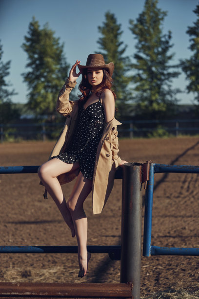 女孩戴着牛仔帽躺在村庄附近的马厩里，一个女人的肖像在阳光下，乡村风格。一个性感的黑发姑娘的肖像。完美的妆容，天然的化妆品图片下载