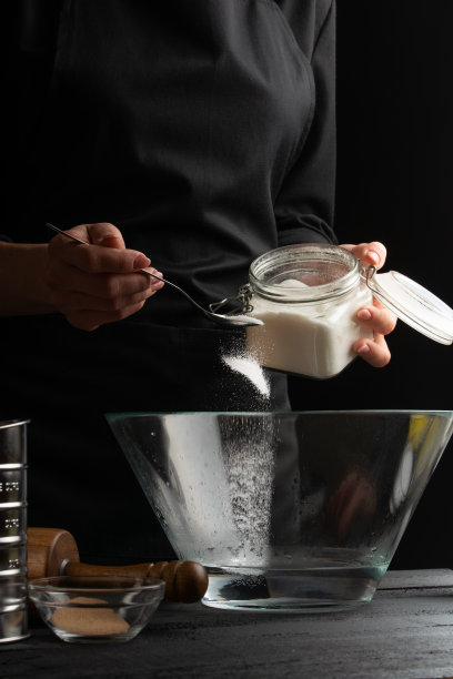 厨师烹饪面团，制作意大利面、披萨、面包和小圆面包，撒上糖，然后冷冻。黑色背景，垂直照片图片下载