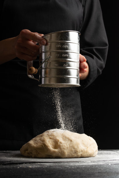 厨师厨师面包师撒面粉在生面团上，用于制作糕点，面包和披萨。食谱和家庭烹饪。烘焙食谱，垂直照片图片下载