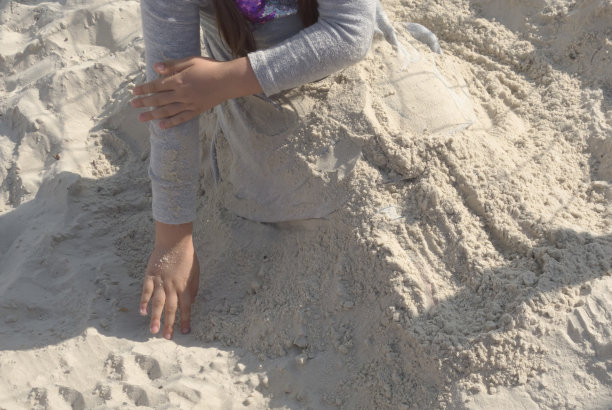 小女孩在海边挖沙子，建城堡图片下载