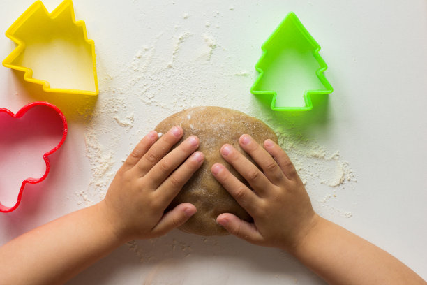 用孩子的手在白底上捏成姜饼生面团图片下载