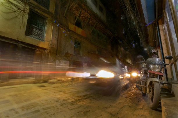 乘汽车和摩托车的旅行者在黑暗的城市街道上探索图片下载