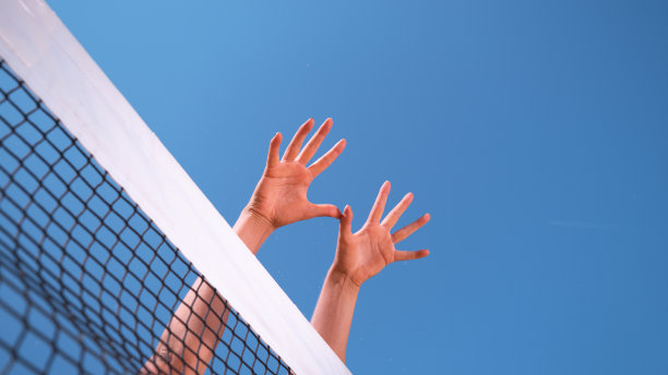 近距离观察:无法辨认的运动女子的双手伸向排球网。图片下载