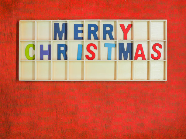 彩色的木制字母或字母圣诞快乐的文本或单词在粗糙生动或充满活力的梯度红色纸纹理和背景。图片下载