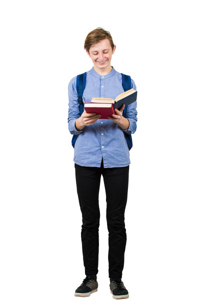 全身像满足学生男孩享受阅读他最喜欢的书孤立在白色的背景。微笑快乐的少年准备考试和会议。图片下载