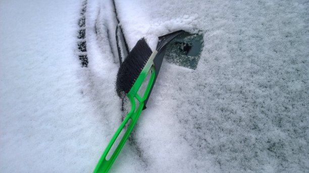 汽车的挡风玻璃结冰了，上面覆盖着雪。刮冰刷用于挣扎清理汽车。冬天来了。结霜的寒冷的天气。城市下雪了。图片下载
