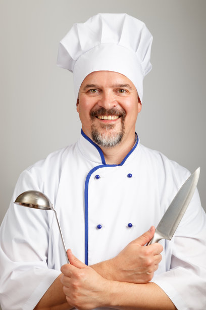一名面带微笑的专业厨师厨师拿着菜刀和汤勺，身穿厨师制服，背景灰色图片下载