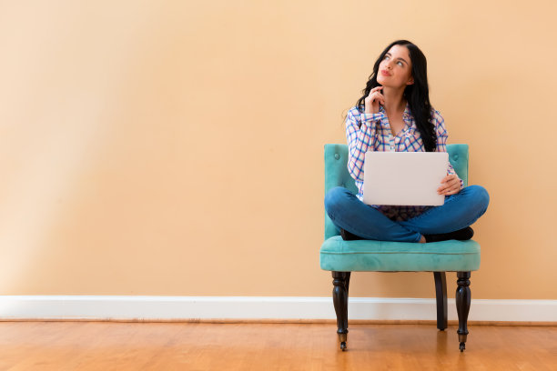 年轻女子拿着一台笔记本电脑，摆出一副若有所思的姿势图片下载