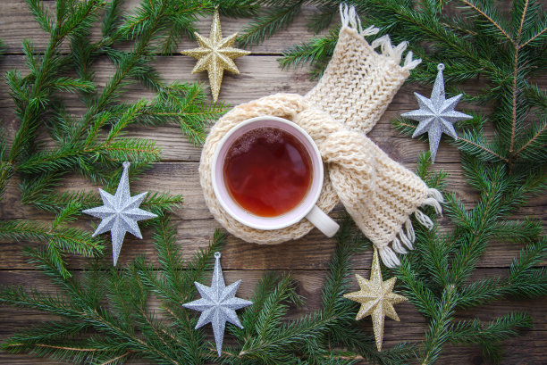 温馨的图片，一杯茶在围巾，圣诞树枝和星星在一个木制的背景图片下载