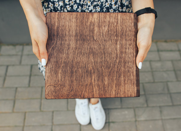 相册的木头在女性手中。手里有木封面的书。木制封面的笔记本。图片下载