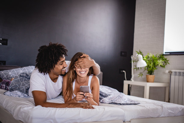 年轻夫妇在床上使用智能手机图片下载