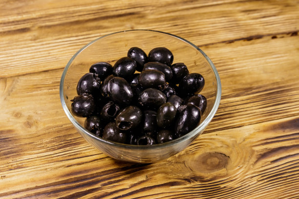 腌黑橄榄放在木桌上的玻璃碗里图片下载
