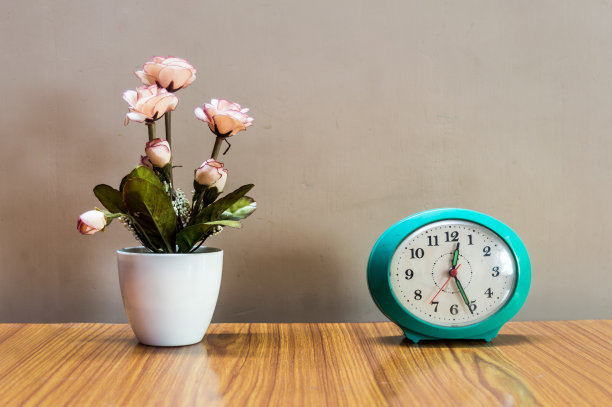 一个花瓶和一个闹钟放在桌子上，与背景隔离。设计元素。为文本复制空间。图片下载