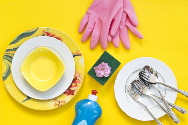 洗碗液瓶附近的盘子在黄色的背景俯视图图片下载