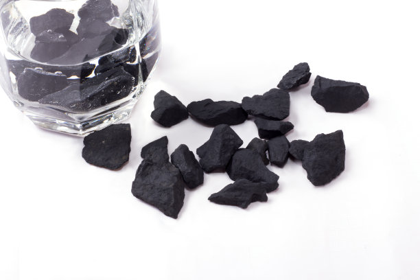 用shungite石头净化的水，放在一个白色背景的玻璃杯里图片下载