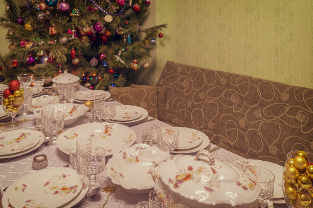 在客厅里，装饰漂亮的圣诞树旁摆着节日餐具的桌子。新年假期在舒适的家的概念。的语气图片下载