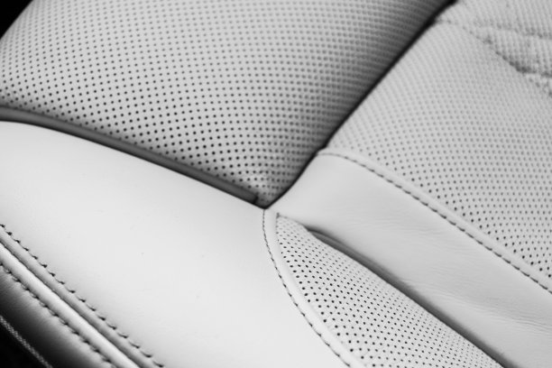 白色皮革内饰在汽车。穿孔白色皮革舒适座椅与缝线隔离在黑色背景。现代汽车内部细节。汽车详细。汽车内部图片下载